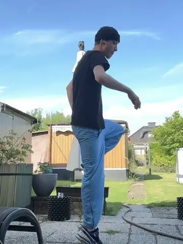 Dancer mid-step in a back garden, knee raised, blue sky behind