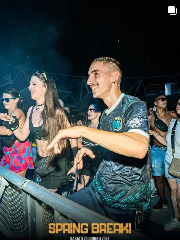 Ninho on the front barrier at an outdoor festival at night, hands mid-move